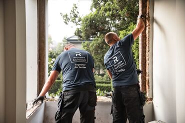 Two Reynaers Aluminium installers dismantling old windows on site.